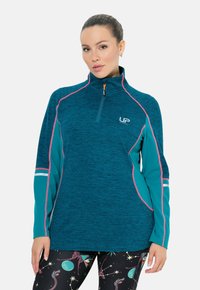 Türkisfarbener Sportpullover mit einem halben Reißverschluss, hellrosa Akzenten und Logo. Mit langen Ärmeln und einem strukturierten Design. Kombiniert mit gemusterten Leggings.