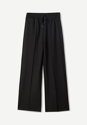 Zwarte wijde broek van zachte stof. Voorzien van een elastische tailleband met een trekkoord en twee zijzakken. Platte voorkant met plooien.