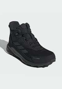Čierne vysoké outdoorové topánky s alebo sieťovinou, zosilnenou špičkou a gumovou podrážkou. Obsahujú technológiu ClimaWarm a ostré akcenty po stranách.