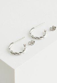 Silberne Creolen mit einem gedrehten Design und polierter Oberfläche. Enthält zwei passende Ohrstecker-Verschlüsse.