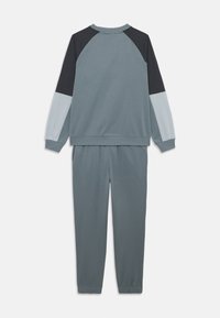 Ensemble en sweat-shirt à manches longues coloré et pantalon de jogging assorti, dans des tons de bleu doux et noir, exposé à plat sur un fond blanc.