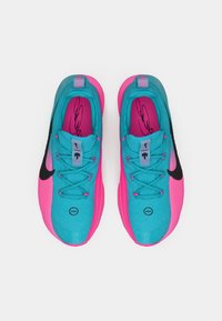 Et par turkise og lyserøde sportsko med sorte Nike swooshes, snørebånd og underskrifter på indersålerne, set ovenfra på hvid baggrund.