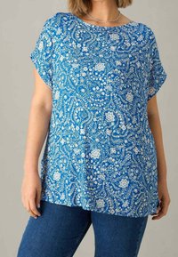 Blå blommönstrad topp med rundad halsringning, korta ärmar och en lös passform. Tillverkad av lätt tyg med en slät yta.