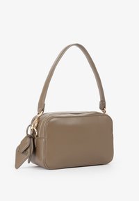 Borsa a tracolla rettangolare in pelle color taupe con una sola tracolla, zip dorata e etichetta coordinata attaccata su sfondo bianco.