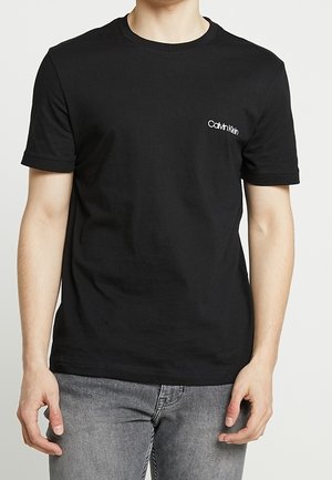 Zwart katoenen T-shirt met korte mouwen en een ronde hals; heeft een klein wit Calvin Klein-logo op de linkerkant van de borst.