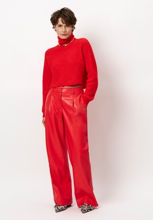 Red cropped turtleneck sweater in soft knit, paired with high-waisted, wide-leg red leather pants. Accented with patterned pointed-toe shoes.