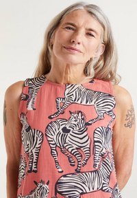 Vestido sin mangas de tejido coral con estampado de cebra en blanco y negro. El diseño incluye varias poses de cebras y una textura suave.