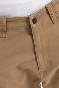 Pantalones de tela marrón con cierre de botón en la parte delantera, detalles de costura visibles y una textura suave. Presentan un acento de botón metálico oscuro.