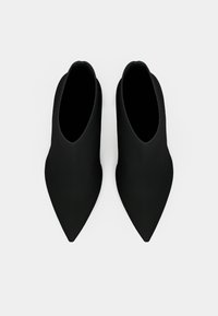 Stivaletti neri alla caviglia con design a punta, texture senza cuciture e una silhouette elegante e minimale. Materiale liscio senza hardware visibile.