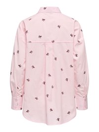 Chemise rose clair à manches longues avec col, ornée de petits motifs de nœuds sombres brodés dispersés dans le dos.