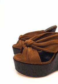 Sandali platform in suede marrone con design annodato sulla parte frontale, tacco a zeppa nero testurizzato, punta aperta e fodera interna liscia.