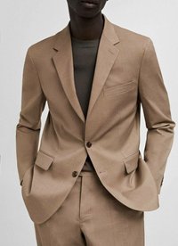Bež blazer iz teksturirane tkanine, ki ima zarezan ovratnik, dve sprednji žep in en žep na prsih. Usklajen s temnim pletenim vrhom.