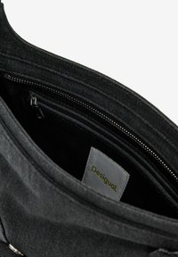 Black denim bag with a structured shape. Interior features multiple pockets and a fabric tag with "Desigual" printed in green. Zipper details visible.