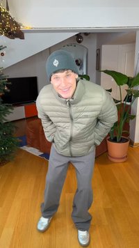 Doudoune vert clair avec fermeture éclair à l'avant, pantalon gris à jambes larges, et baskets argentées. Un bonnet foncé complète la tenue. Cadre intérieur.