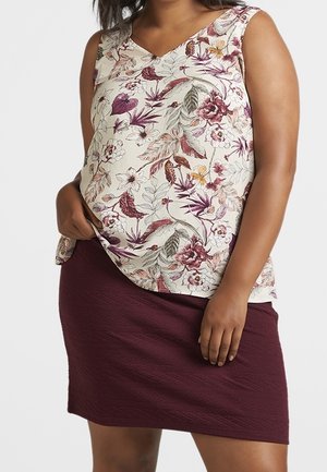 Ärmelloses florales Oberteil in Creme mit violetten und rosafarbenen Tönen, kombiniert mit einem strukturierten burgunderfarbenen Rock. V-Ausschnitt, lässige Passform.