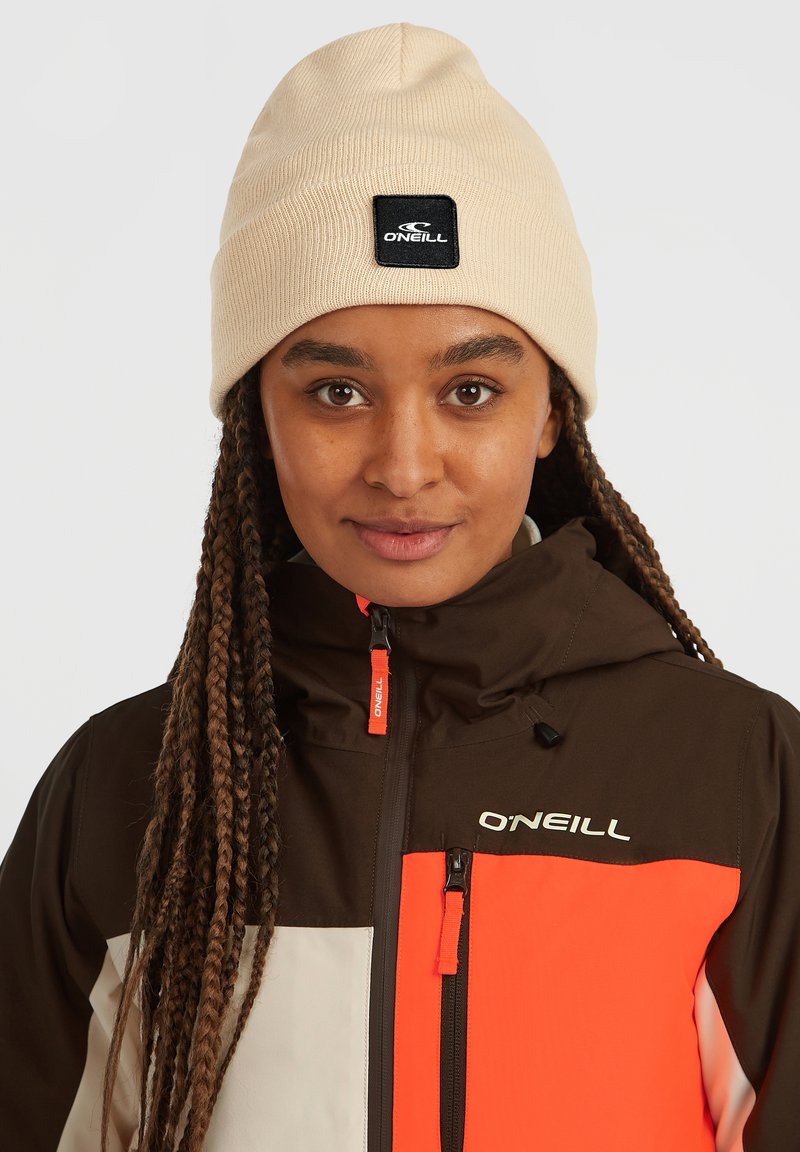 Beige strikket hue med et sort mærke med teksten "ONEILL." Brun og orange jakke med farveblokeret design, der har logoer og lynlåse.