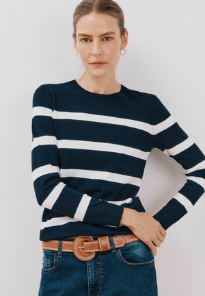 Pull bleu marine avec des rayures blanches horizontalement, col rond et manches longues. Associé à un jean bleu et une ceinture marron avec une boucle ronde.