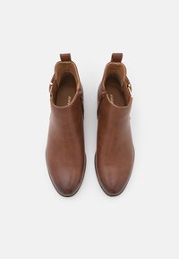 Stivaletti in pelle marrone con finitura liscia, punta affusolata, zip laterale e una piccola linguetta sul retro per facilitarne l'indossamento.