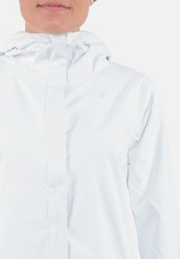 Giacca bianca impermeabile con cappuccio, caratterizzata da una texture liscia, chiusura a cerniera frontale e un piccolo logo sul petto.