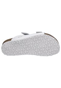 White sandal with cork footbed, textured upper, and adjustable straps. White rubber outsole features a zigzag tread design for grip.
