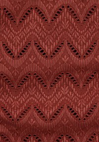 Rozsda színű kötött szövet ismétlődő hullámos csipkemintával, amely apró nyitott lyukakat és függőleges bordás textúrákat tartalmaz.