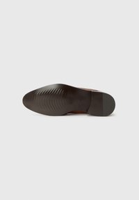 Suela de zapato de cuero marrón con una superficie suave y una sutil textura acanalada; presenta una forma redondeada y un tacón ligeramente elevado.