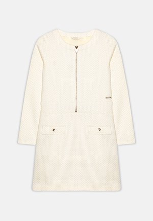 Robe couleur crème avec manches longues, fermeture éclair à l'avant, tissu texturé, deux poches avant et accents dorés. Design simple et coupe droite.