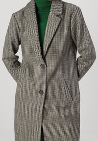 Abrigo de doble botonadura con estampado de pata de gallo en gris y negro, con cuello de muesca, dos bolsillos delanteros y botones marrones. Tejido texturizado.