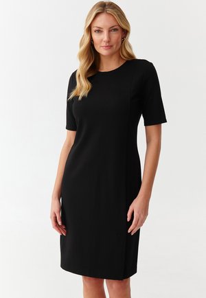 Juoda trumpa palaidinė su apvaliu kaklu, tiesaus kirpimo ir šoninėmis plyšiais. Pagaminta iš lygaus audinio, siūlanti elegantišką prigludimą.