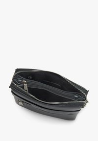 Černá kožená taška se dvěma zipovými přihrádky, s prvky ze stříbrného kovu a hladkou texturou. Přihrádky jsou podšité černou látkou.