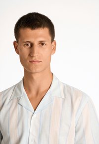 Camicia a maniche corte in tessuto leggero con righe verticali in azzurro chiaro e beige, dotata di un colletto morbido e chiusura con bottoni.