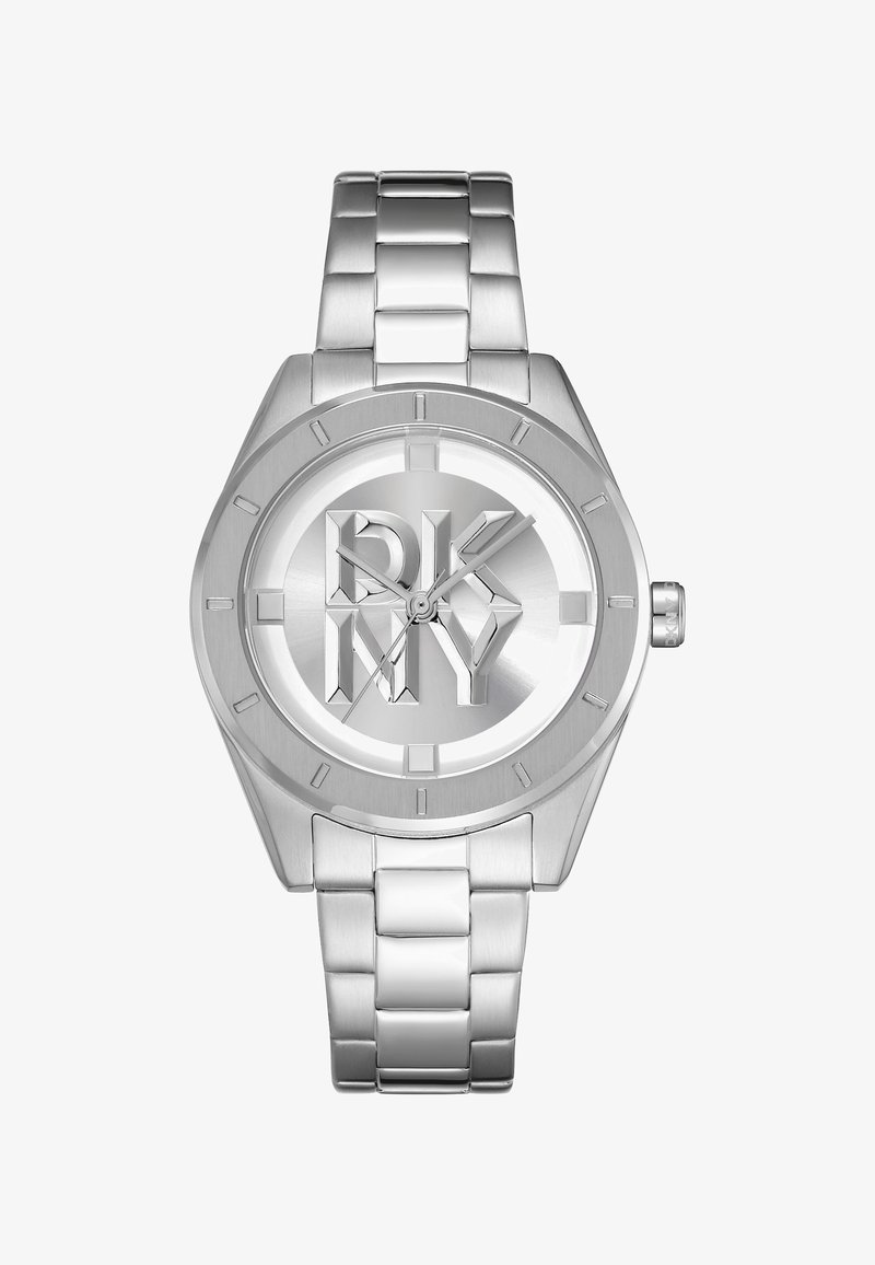 Montre en acier inoxydable argenté avec un boîtier octogonal, grand logo DKNY sur le cadran et un bracelet à maillons. Index horaires minimalistes.