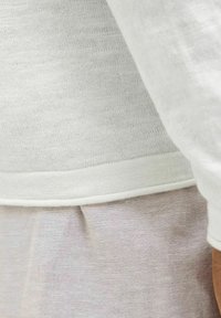 Maglietta in tessuto lavorato a maglia bianco con finitura texture, caratterizzata da un orlo arrotondato e uno strato inferiori in lino grigio chiaro a contrasto.