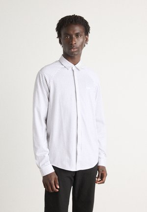 Wit overhemd met lange mouwen en een ruitpatroon, met een button-down kraag en een borstzak. Gecombineerd met zwarte broeken van een getextureerde stof.