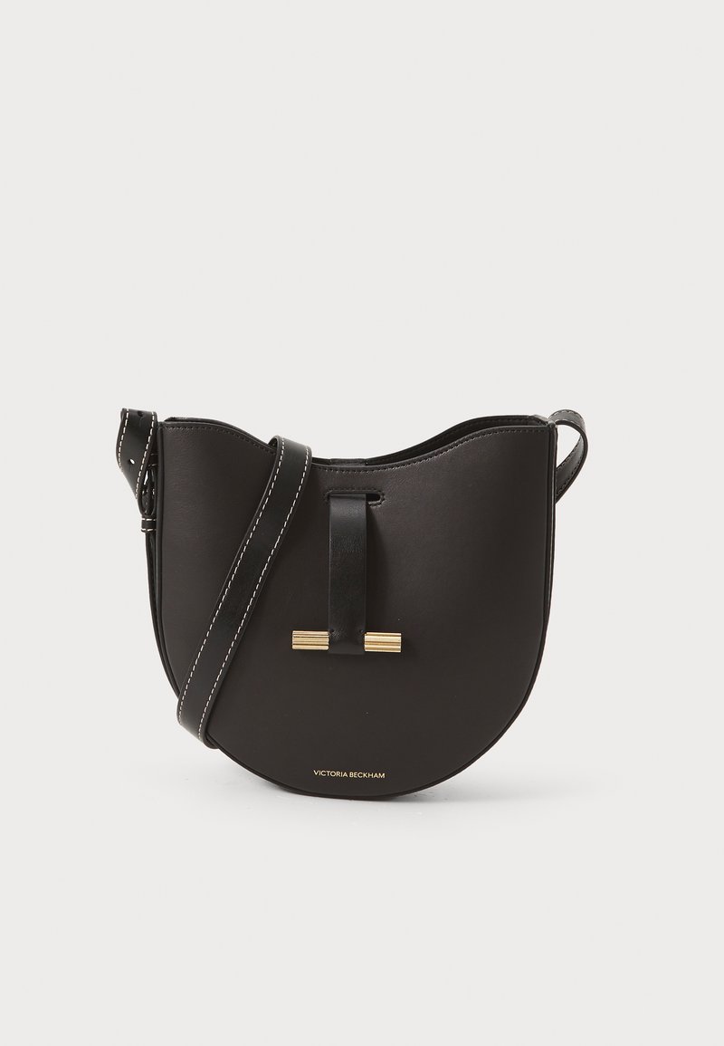 Μαύρη δερμάτινη τσάντα ώμου με καμπυλωτό σχήμα, χρυσά μεταλλικά αξεσουάρ και αντίθετη λευκή ραφή. Περιλαμβάνει ρυθμιζόμενο λουρί.