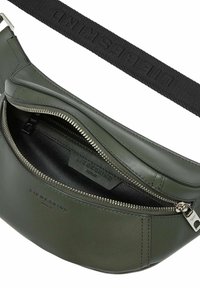 Olivgrüne Leder-Tasche mit Reißverschluss, strukturiertem Tragegurt und geprägtem Branding. Das Innere verfügt über eine glatte Fütterung und eine Reißverschlusstasche.