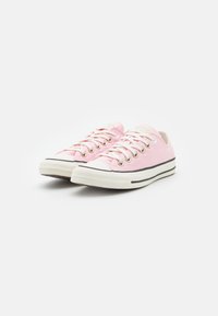 Rosa canvassneakers med vita gummisulor, svarta ränder och sex metalögon för snören, med en rundad tådesign.