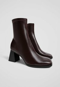 Burgundy nahkasaappaat nilkkapituisilla, neliömäisellä kärjellä, lohkareen korkolla ja sivuvetoketjulla. Sisältää kontrastiväriset ompeleet ja sileän pinnan.