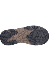 Sort og brun gummisål med en tekstureret overflade, der har geometriske mønstre og et stjerneagtigt design i midten.
