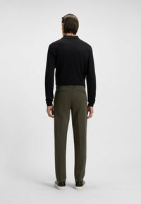 Zwarte lange mouwen top met een kraag, gecombineerd met olijfgroene broek. Heeft een eenvoudig ontwerp met een rechte pasvorm en achterzakken.