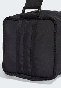 Zwarte stoffen tas met een rechthoekige vorm, voorzien van drie verticale strepen en een dikke draagriem. Glad materiaal met verstevigde stiksels.