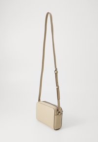 Beige axelremsväska gjord av texturerat material, med rektangulär form, justerbar rem och kontrasterande sömmar längs kanterna.