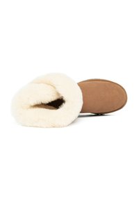 Zapatilla de ante marrón con un suave forro de piel blanca, collar redondeado, suela plana y construcción simple, diseñada para comodidad y calor.