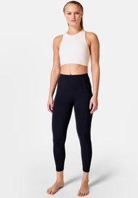 Top atletico bianco corto con texture a costine abbinato a leggings neri a vita alta con dettagli nelle cuciture e finitura liscia.
