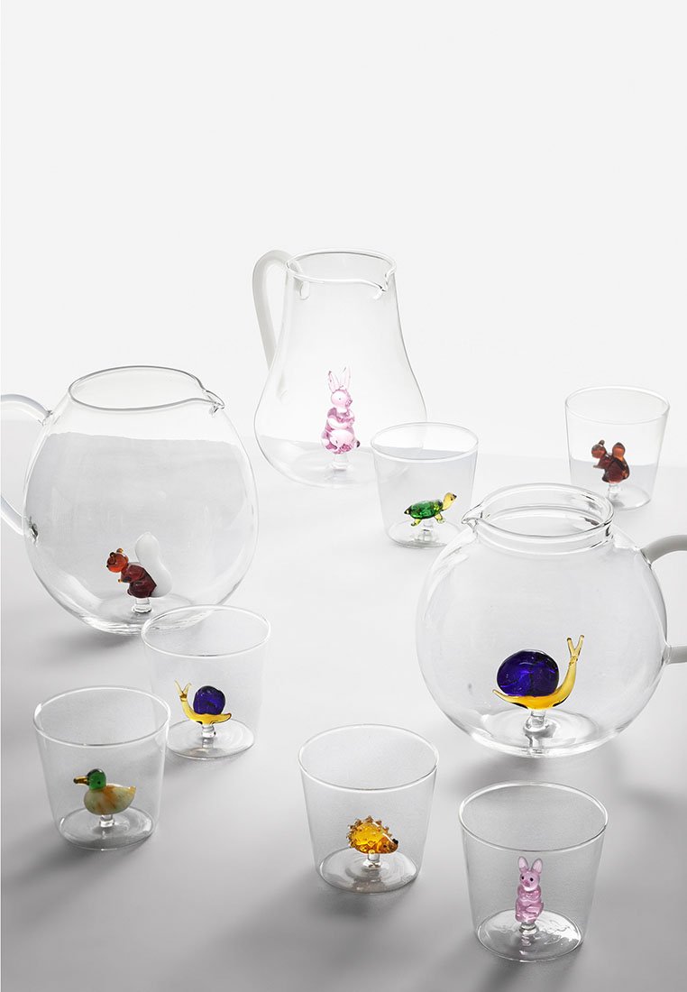 Jarras y tazas de vidrio transparente contienen pequeñas figuras de animales de vidrio colorido, incluyendo un caracol, un conejo, una ardilla, una tortuga, un pato y un erizo.