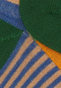 Tessuto a maglia multicolore con sezioni verdi, blu, gialle e color sabbia. Include motivi a righe e solidi con una finitura testurizzata.
