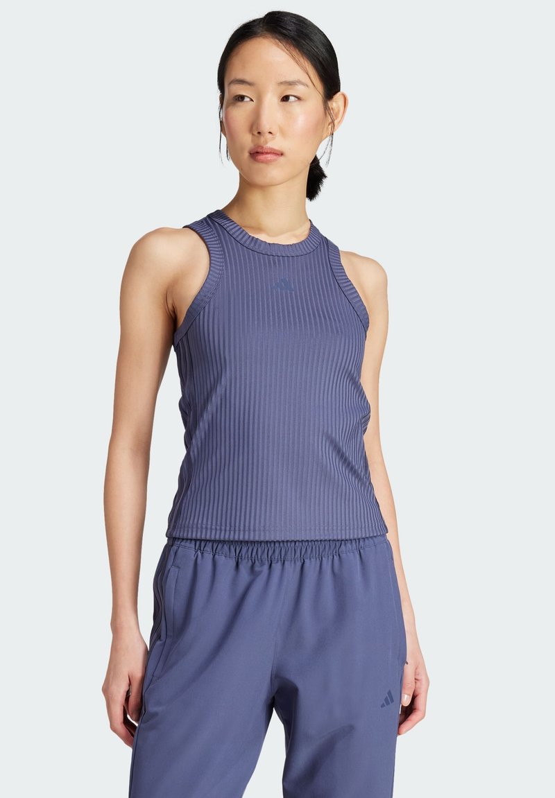 Paarse geribde tanktop met een ronde halslijn en subtiele logodetails, gecombineerd met bijpassende losvallende sportbroek. Zacht, rekbaar materiaal.