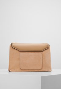 Borsa in pelle marrone chiaro con una parte superiore liscia e un corpo in suede testurizzato. Presenta una tasca anteriore rettangolare e cuciture a contrasto.