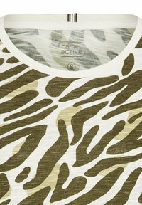 Bomulds T-shirt med rund halsudskæring og grønne og sandfarvede zebra striber på en hvid baggrund. Har et mærke inde i kraven.