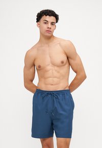 Blaue Badeshorts aus einem leichten Stoff mit elastischem Bund und Kordelzug. Sie besitzen eine glatte Textur und ein schlichtes Design.